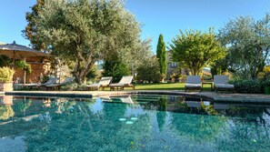 A clear swimming pool with lounge chairs and a stone building in the background.