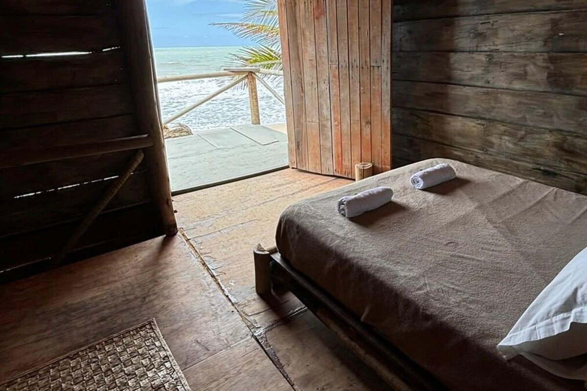 Une pièce en bois avec un lit, une fenêtre et une vue sur la plage.