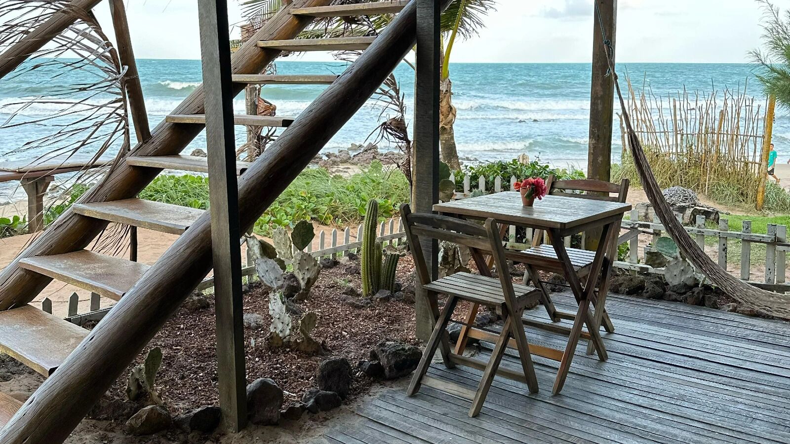 Une terrasse en bois avec une table et des chaises, donnant sur l’océan.