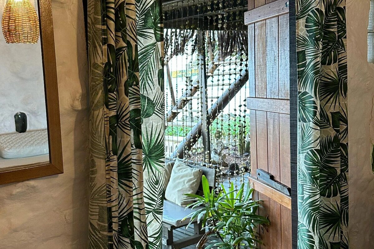 Une pièce avec un hamac, un banc en bois et une vue sur un jardin.