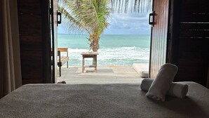 Une chambre avec un lit, une table en bois, une chaise et une vue sur l’océan.