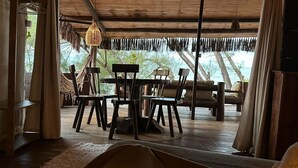 Un espace de vie à aire ouverte avec un plafond en bois, un luminaire suspendu et une vue sur l’océan.