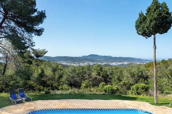 A swimming pool with a view of a city and mountains in the background.