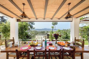 A dining table set for breakfast with a view of mountains and greenery.