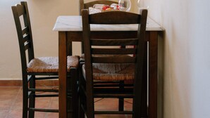 A dining area with a table and two wooden chairs. - Cozy Gem With Access to a Sparkling Shared Pool (Samos)