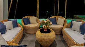 Un área de descanso con mobiliario de mimbre y una mesa central con un arreglo floral.