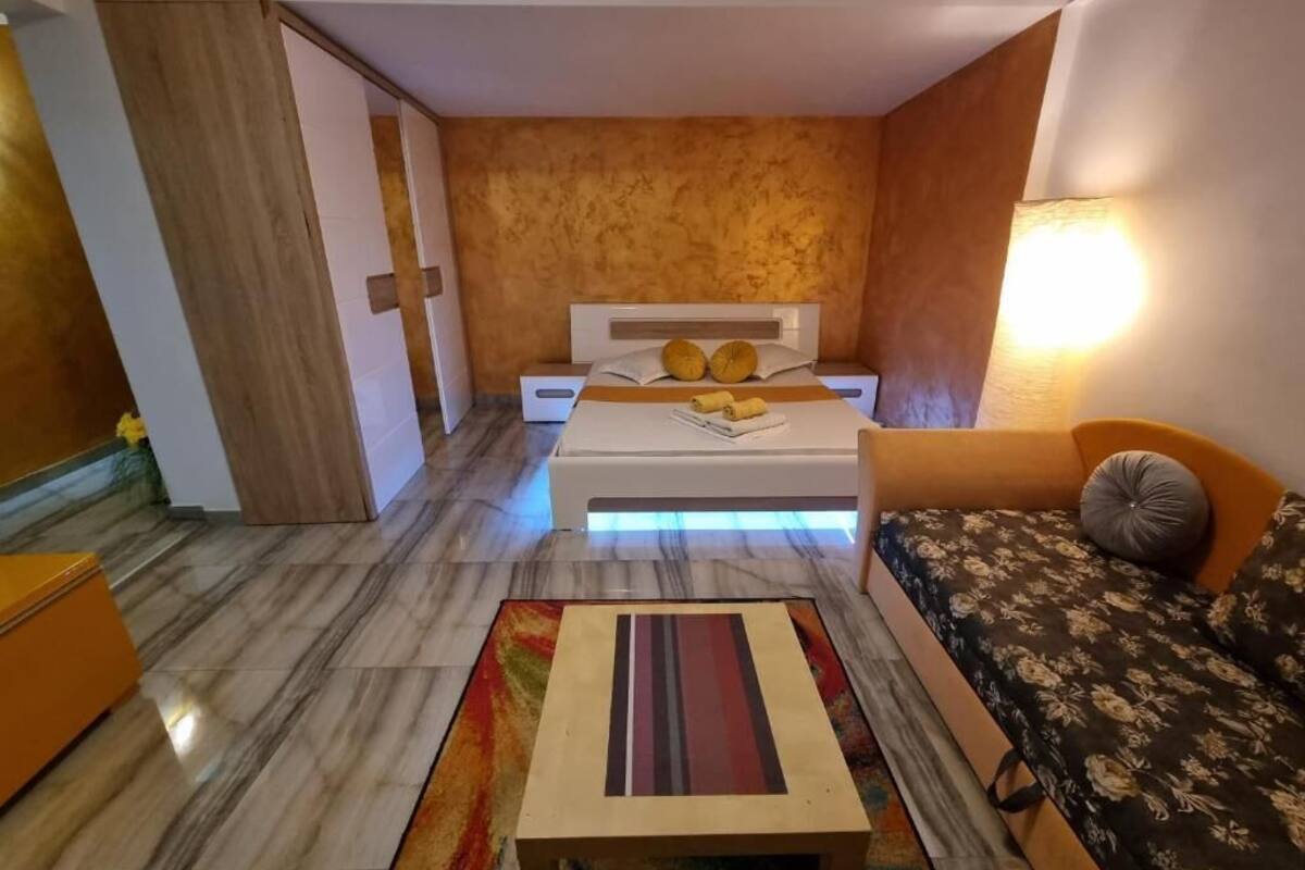 Een moderne slaapkamer met een bed, nachtkastjes, een bank en een klein tafeltje.