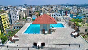 A rooftop swimming pool with a red roof, surrounded by lounge chairs and a table. - 600sqft,5 Elite Stay with Pool, Sauna and Gym in Bashundhara (Dhaka)