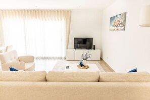 Un salon avec un canapé, une table basse, un téléviseur et un tableau accroché au mur.