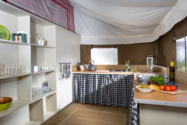 Una cocina compacta con estantes blancos, un mantel a cuadros y una ventana con vistas.