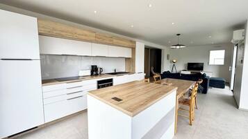 Une cuisine moderne avec des meubles blancs, un îlot central en bois et un coin repas avec des chaises.