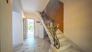 A marble staircase with ornate metal railings leading to a landing.