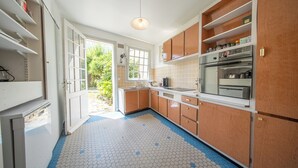 A kitchen with wooden cabinets, a refrigerator, and a window.