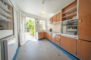 Una cocina con armarios de madera, un refrigerador y una ventana.