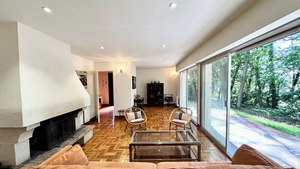 Amplia sala de estar con chimenea, asientos cómodos y grandes ventanas que ofrecen vistas al exterior.