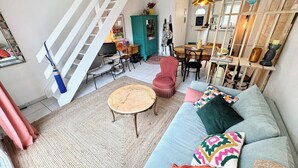 Un salón amplio con escaleras, un sofá, una mesa de centro redonda y un comedor.