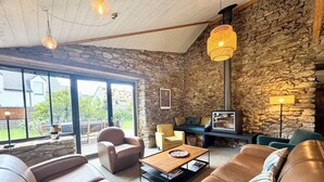 Un salon chaleureux avec des canapés en cuir, un mur en pierre et une cheminée.