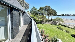 A modern house with a balcony overlooking a beach and a body of water.