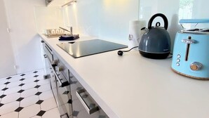 A modern kitchen with a white countertop, a kettle, a toaster, and a sink.