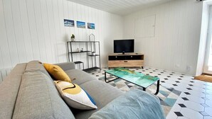 A modern living room with a grey sofa, a coffee table, a TV, and a patterned floor.