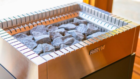 A Harvia portable heater with a metal frame and a compartment filled with charcoal briquettes.