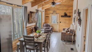 L’intérieur d’un chalet confortable, avec une salle à manger, un canapé et une cheminée.