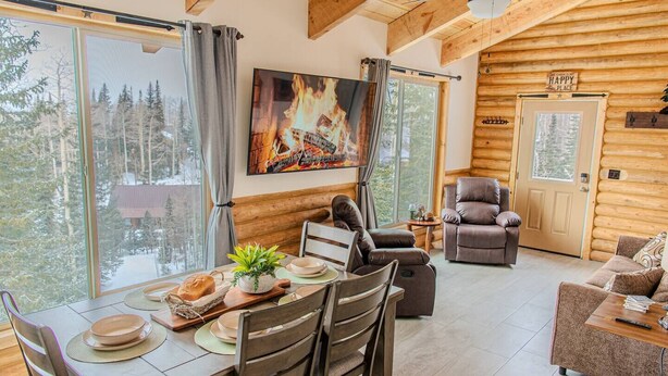 Un intérieur de chalet chaleureux avec un coin repas, une cheminée et un espace salon confortable.