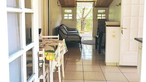 Un vaste espace de vie doté d’un haut plafond, une table à manger avec des chaises, un canapé et un coin cuisine équipé d’un réfrigérateur.