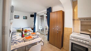 A compact kitchen with a dining area, a wooden wardrobe, and a built-in oven.