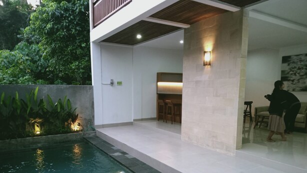 Un espace piscine extérieur moderne doté d’une terrasse en bois, d’un coin salon et d’un mur en pierre.
