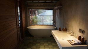 Een badkamer met een vrijstaand bad, een wit wastafel en een raam met zonwering.