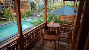 Une terrasse en bois avec une piscine, des chaises et des parasols.
