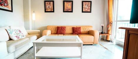 Un salon avec un canapé, une table basse et des tableaux encadrés accrochés au mur.