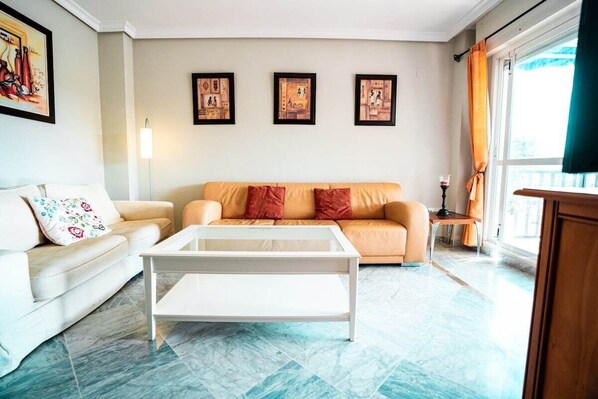 A living room with a sofa, a coffee table, and framed pictures on the wall.