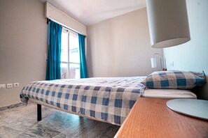 A hotel room with a bed, a desk, a lamp, and a window with curtains. - Locrimar, 3 bedroom apartment in Puerto Banus (Marbella)