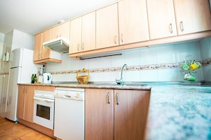 A kitchen with wooden cabinets, a white stove, a dishwasher, and a tiled backsplash. - Locrimar, 3 bedroom apartment in Puerto Banus (Marbella)
