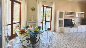Un ampli saló amb taula de menjar de vidre, televisió i una llar de foc.