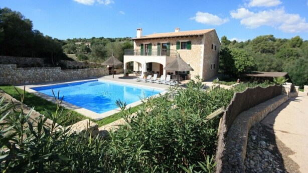 Una villa con piscina, muros de piedra y jardín.