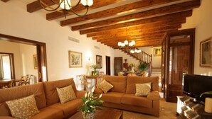 Amplia sala de estar con techo de madera, un sofá grande, una mesa de centro y un televisor.