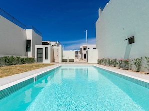 Relax by the pool surrounded by lush greenery and a clear blue pool.