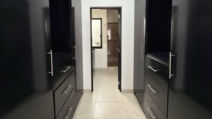 A narrow hallway with dark-colored wardrobes on either side, leading to a door at the end.