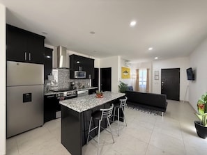 Enjoy cooking in the well-equipped kitchen with a central island, stove, and refrigerator.