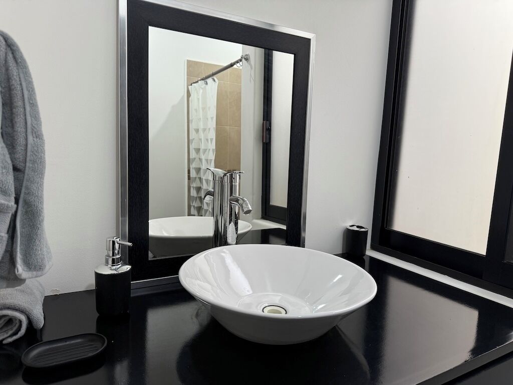Een moderne badkamer met een wit wastafelmeubel, een grote spiegel en een zwart aanrecht.