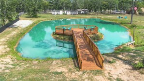 A rectangular pond with a wooden deck and chairs, surrounded by grass and trees. - Finca Agave Deluxe Home No. 6 Buttercup (Hempstead)