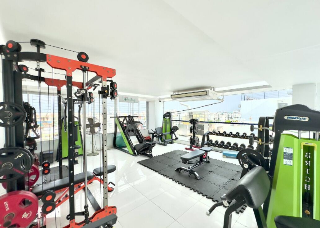 A gym with various exercise equipment, including weight machines, free weights, and cardio machines.
