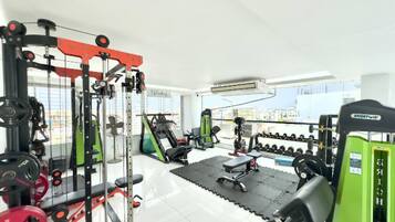 Uma academia com diversos equipamentos de exercícios, incluindo aparelhos de musculação, pesos livres e máquinas cardiovasculares.