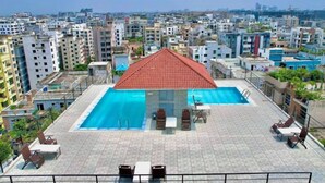 Una piscina en la azotea con techo rojo, rodeada de sillones de descanso y una mesa.