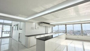 Una cocina moderna con una isla grande, armarios blancos y vistas a la ciudad a través de amplios ventanales.