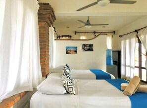 A hotel room with two beds, a ceiling fan, and a brick wall. - Jardin De Playa Sayulita (Sayulita)