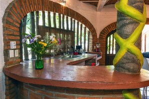 A kitchen with a brick archway, a green vase with flowers, and a unique yellow column. - Jardin De Playa Sayulita (Sayulita)